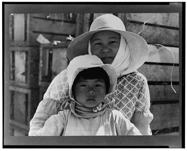 A mother and daughter pose wearing sunhats